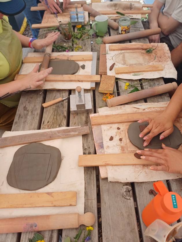 Individuals rolling out clay using wooden guides and pins