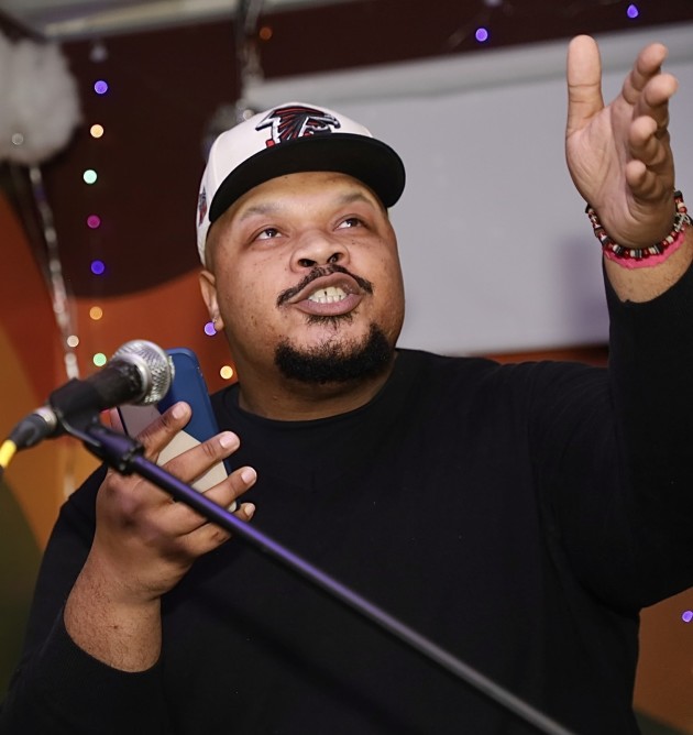 Man reads poetry into a microphone. Photo credit goes to ASTP Photography.